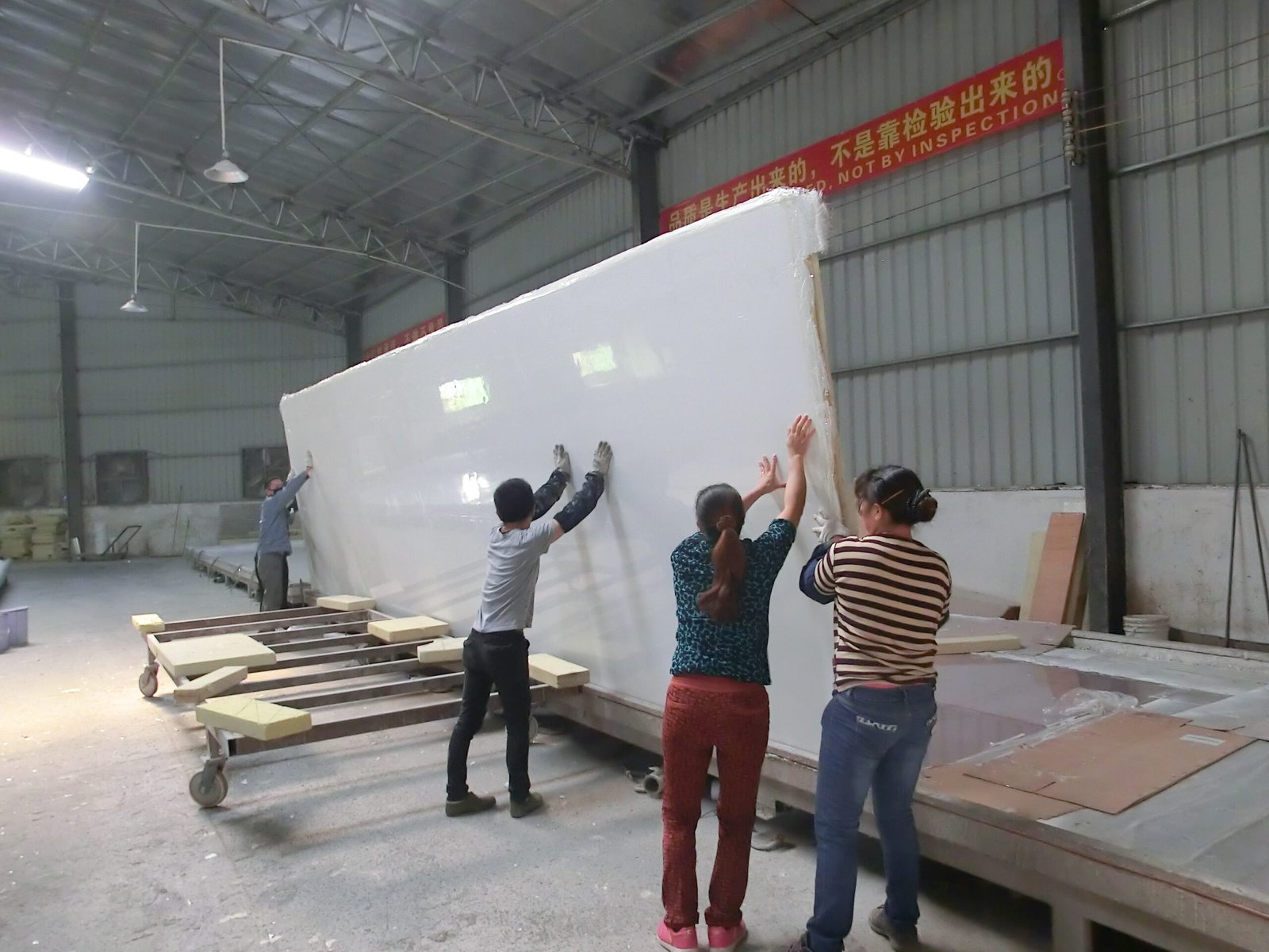 Workers handling an insulated panel during production