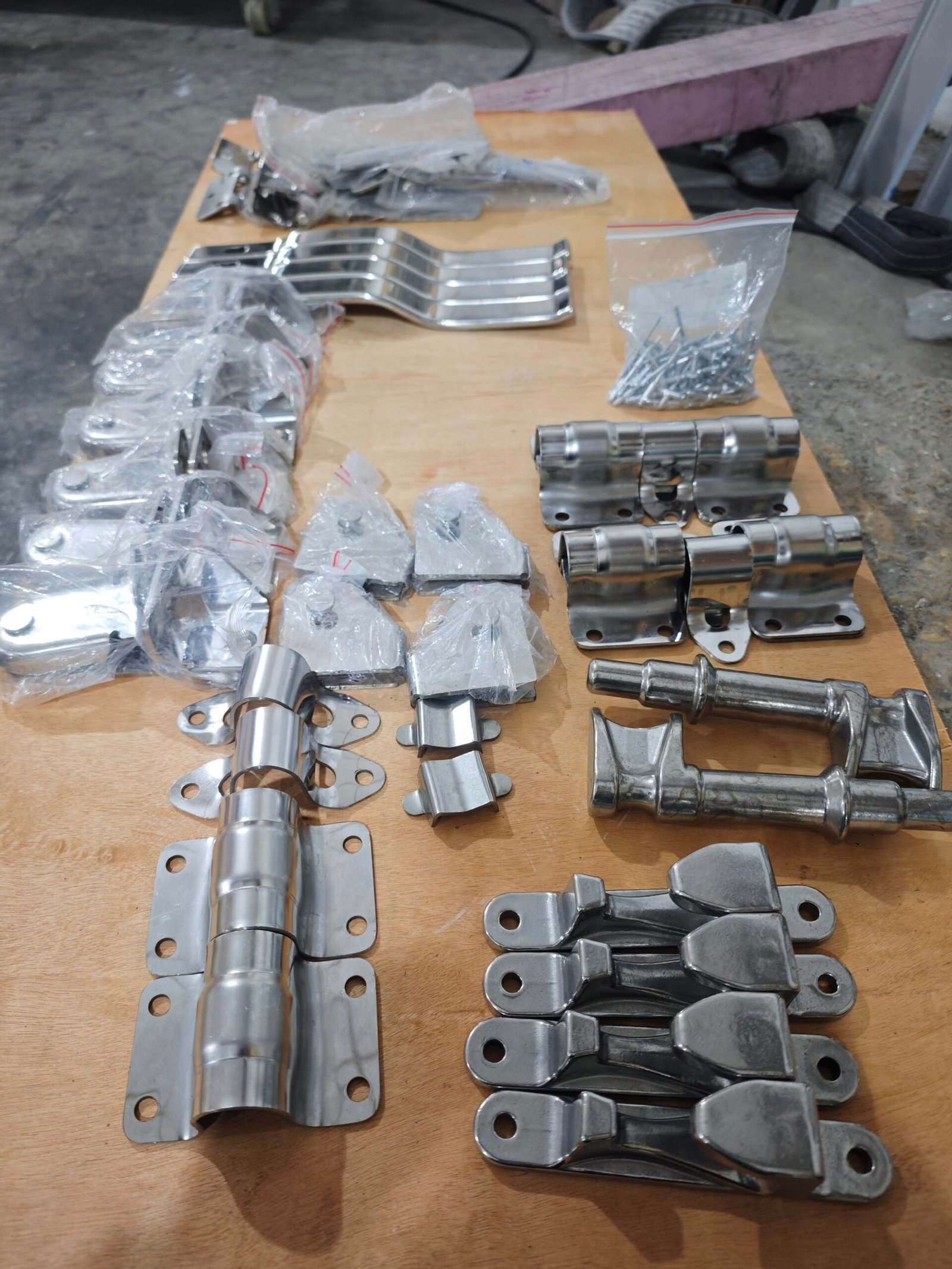 Door hinges, locking handles and mounting hardware arranged on a board.