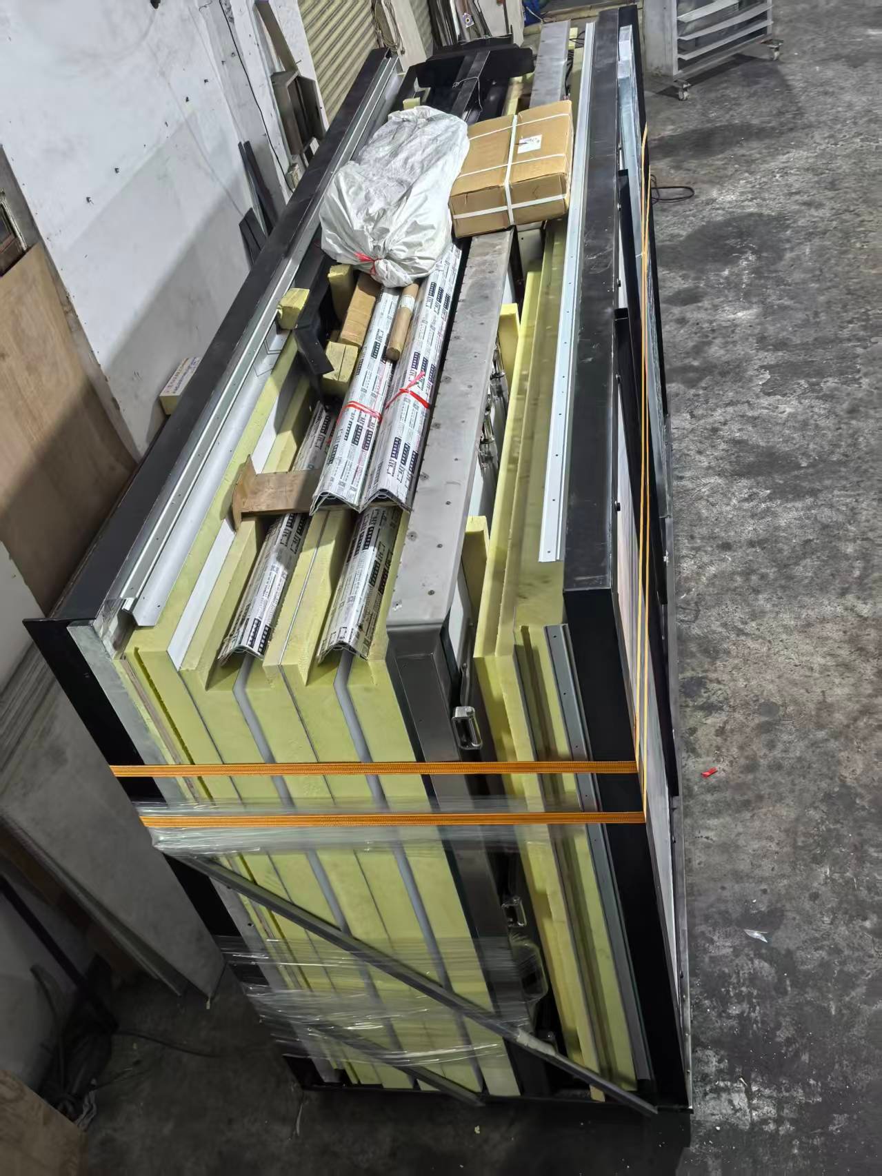 Insulated panels, edge profiles and wrapped components grouped and strapped for packing.