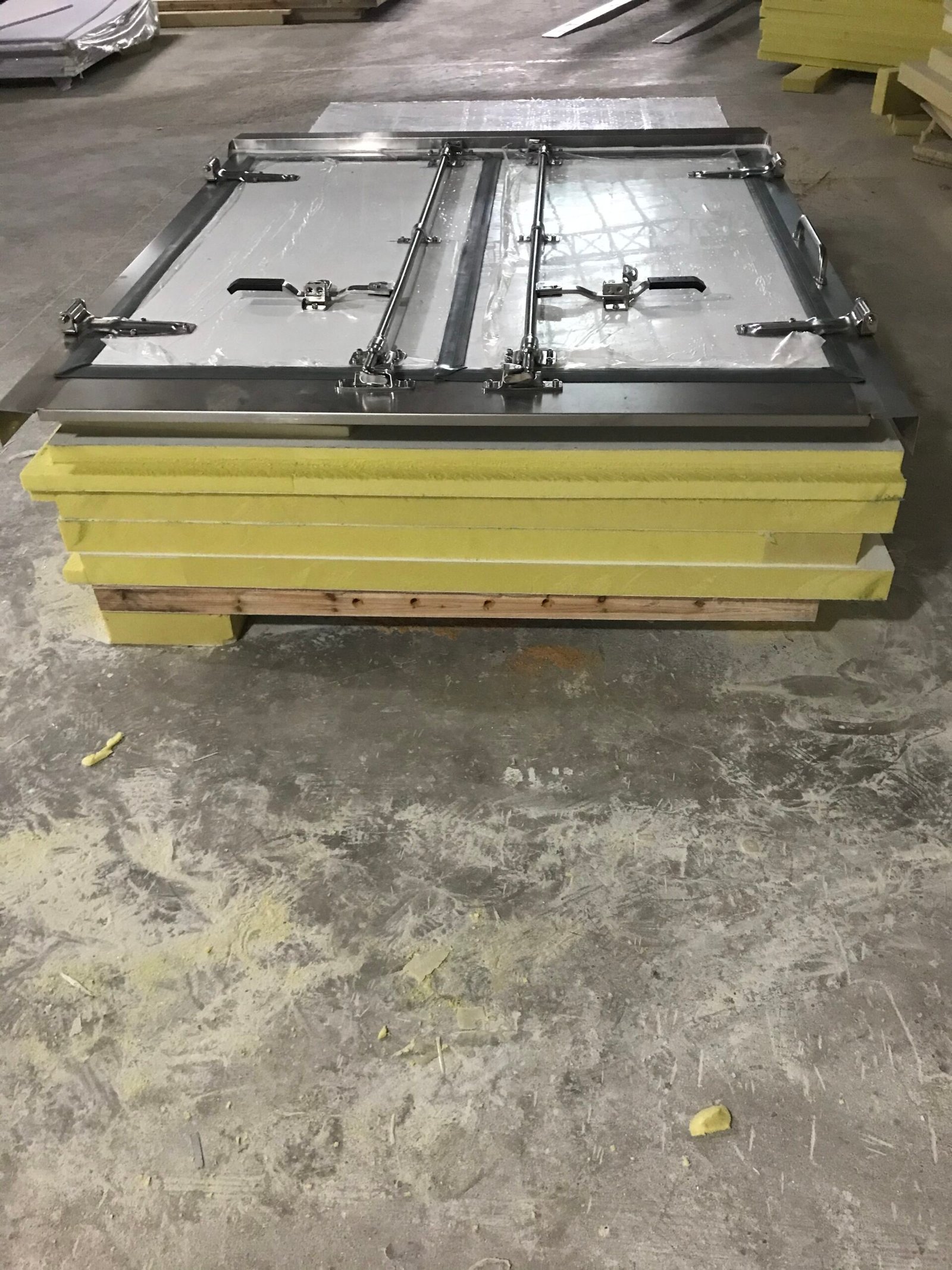 Insulated body panels stacked beneath a double-door assembly with locking rods.