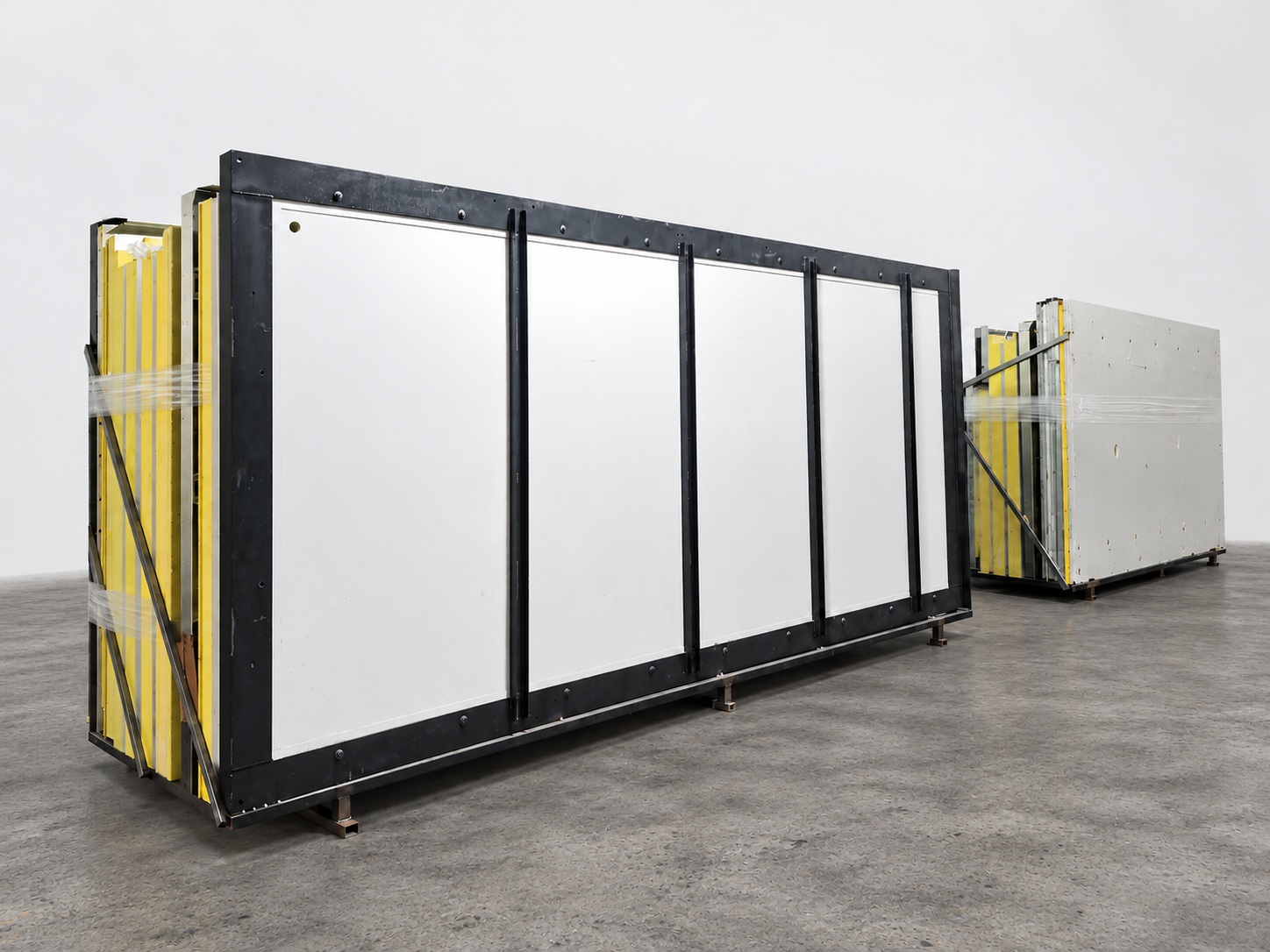 Body panels and black frames on a matte concrete floor with an edited grey-white backdrop.